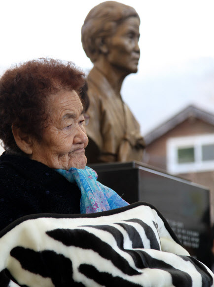 “이 恨을 어찌 풀꼬”  1일 경기 광주시 퇴촌면에 있는 일본군 위안부 피해 할머니들의 보금자리인 나눔의 집에서 3·1절을 맞아 열린 위안부 피해자 추모제에서 피해자인 김군자(86) 할머니가 ‘해결되지 않은 위안부’ 문제 탓에 입술을 굳게 다문 채 추모사를 듣고 있다. 뒤쪽에 일본군의 만행을 알리는 데 힘쓰다 지난 1997년 숨진 강덕경 할머니의 흉상이 보인다. 연합뉴스 