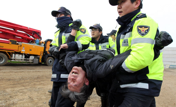 9일 오전 제주해군기지 건설 공사장 펜스를 뜯어내고 안으로 진입했던 송영섭 목사가 경찰에 연행되고 있다. 연합뉴스
