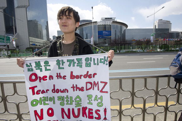 핵안보정상회의를 하루 앞둔 25일 오후 청소년 환경평화운동가인 미국 국적의 조너선 리(15)가 서울 강남구 삼성동 코엑스 앞에서 한반도 평화를 호소하며 1인 시위를 하고 있다. 뉴스1