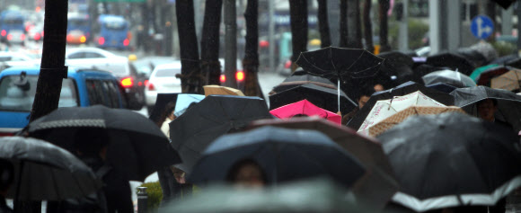일부 지역에 대설주의보와 강풍경고가 내려진 3일 오전 강한 바람과 함께 진눈깨비가 내리는 서울 명동거리에서 시민들이 우산을 쓰고 출근하고 있다. 연합뉴스