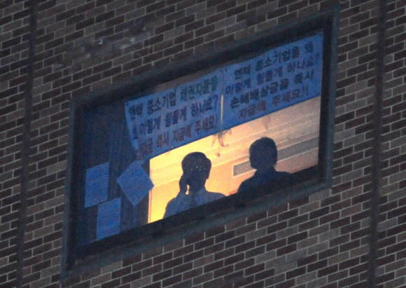 3일 서울 중구 장충동 신라호텔 14층 객실에서 점거 농성을 하고 있는 ‘엔텍 중소기업 피해배상촉구 채권단’이 전화를 하며 창밖 상황을 지켜보고 있다. 박지환기자 popocar@seoul.co.kr