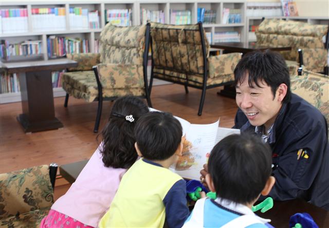 문건민(오른쪽) 창원우체국 집배원이 동료와 함께 만든 지역 아동보육시설의 ‘꿈꾸는 작은 도서관’에서 어린이들의 독서를 도와주고 있다.  우정사업본부 제공