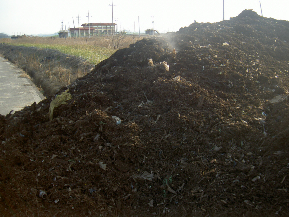 전남의 한 지방도로변에 음식물쓰레기 중간 처리 가공물이 산더미처럼 쌓인 채 방치돼 있다.