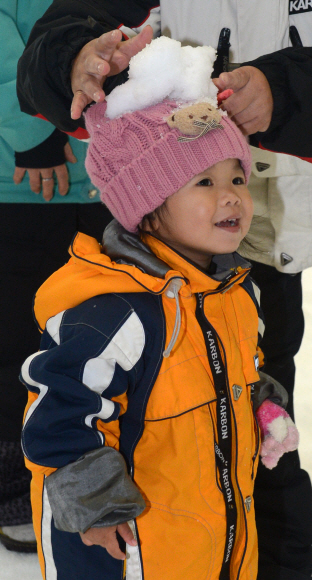웅진플레이도시에서 타이완 관광객이 태어나서 눈을 처음 본 아이의 모자 위에 눈덩이를 올려놓으며 장난을 치고 있다.