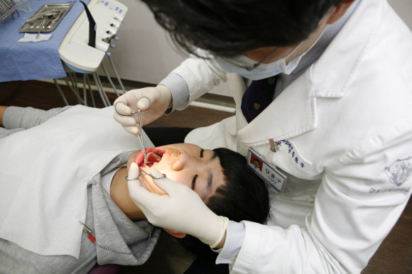 치아 교정치료는 6~7세 무렵에 문제를 찾아 치료하는 게 바람직하다. 치료 효과가 좋은 것은 물론 비용 부담도 크게 덜 수 있기 때문이다. 사진은 강윤구 교수가 교정치료를 하는 장면.
