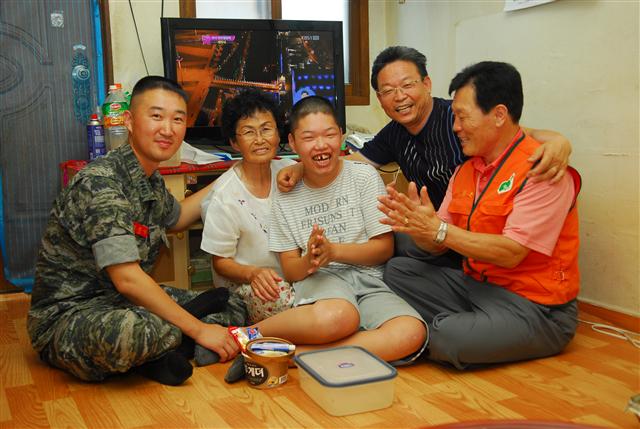 이찬우(37·왼쪽) 대위가 28일 한국장애인봉사협회 관계자들과 함께 지적장애자 1급 서영호(21·왼쪽 세번째)씨의 대구시 동구 입석동 집을 방문해 빨래 등 봉사활동을 한 다음 즐거운 시간을 보내고 있다. 해병대 제공