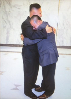 김정은(왼쪽) 북한 국방위원회 제1위원장이 지난달 22일 자신의 품에 안긴 채 울먹이는 후지모토 겐지를 감싸안고 있다.  TBS 화면 캡처