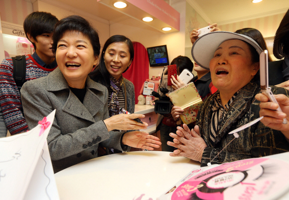 박근혜(왼쪽) 새누리당 대선 후보가 31일 오후 경기 수원역 앞의 화장품 가게를 방문해 시민들에게 사인을 해준 뒤 활짝 웃고 있다. 이호정기자 hojeong@seoul.co.kr 