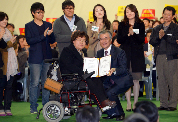 문재인(앞줄 오른쪽) 민주통합당 대선 후보가 4일 경기 고양시 일산 킨텍스에서 장애인등급제 폐지를 제안한 이라나씨에게 ‘국민의 명령1호’ 증서를 수여한 뒤 기념 사진을 찍고 있다.  이호정기자 hojeong@seoul.co.kr