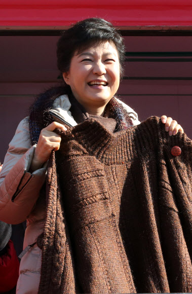 새누리당 박근혜 대선후보가 6일 오전 안산시 단원구 중앙역 유세에서 한 지지자가 직접 짠 스웨터를 선물 받은 뒤 들어보이며 밝게 웃고 있다.  연합뉴스