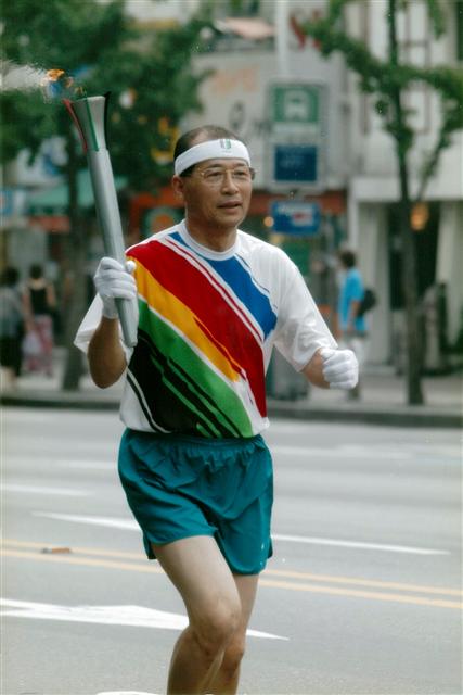 우리금융지주 회장이었던 2002년 부산아시안게임 때 서울 종로 거리에서 성화봉송 주자로 나서며. 