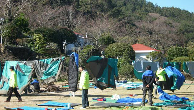 푸른 남해 바다가 보이는 운동장에서 퇴소를 앞두고 참가자들이 침구류를 정리해 말리고 있다.