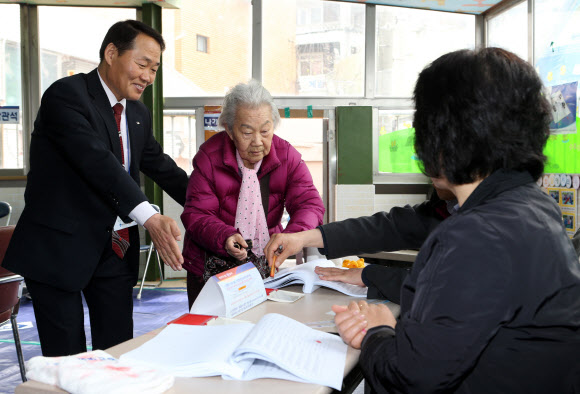 4.24 재·보궐선거 투표일인 24일 오후 부산 영도구 신선동 제2투표소에서 시민이 선관위 관계자의 안내를 받으며 투표용지를 받고있다. 연합뉴스