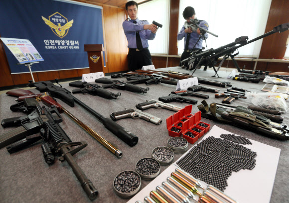 24일 인천 해양경찰서 소속 해경들이 압수한 불법 밀반입 총기류를 살펴보고 있다.  연합뉴스