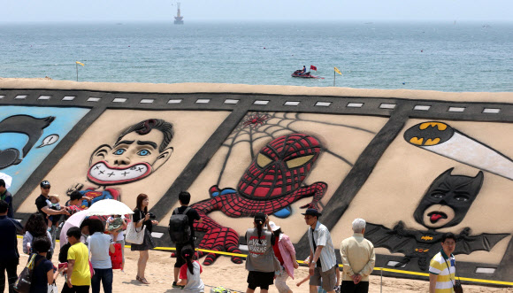 6일 부산 해운대해수욕장에서 피서객들이 모래조각을 구경하고 있다. 영화를 주제로 하는 해운대모래축제는 7일 개막한다. 연합뉴스