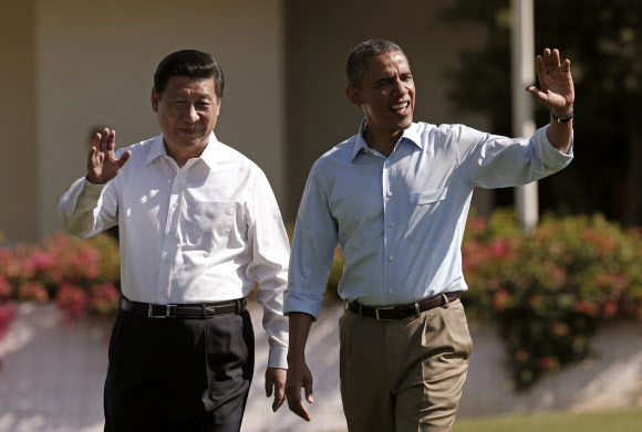버락 오바마(오른쪽) 미국 대통령과 시진핑 중국 국가주석이 정상회담 이틀째인 8일(현지시간) 캘리포니아주 랜초미라지 서니랜즈의 애넌버그 별장에서 함께 거닐던 중 손을 들어 인사를 하고 있다. AFP 연합뉴스