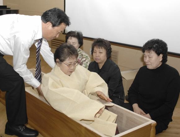 서울시 마포구의 ‘웰다잉 프로그램’ 참가자들이 수의을 입고 직접 관에 들어가보는 입관 체험을 하고 있다. 마포구청 제공 