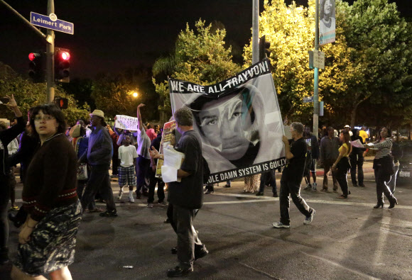 이날 평결에 반대하는 시위자들이 캘리포니아주 로스앤젤레스 파크라브레아 아파트 인근에서 “우리는 모두 (총살당한 흑인소년)트레이본이다”라고 쓰여진 현수막을 들고 행진하고 있다. 샌포드 AP 연합뉴스