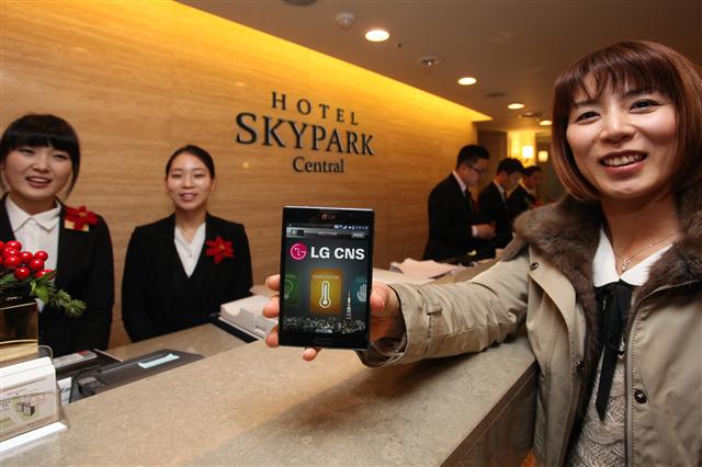 LG CNS 관계자가 호텔 체크인부터 체크아웃까지 스마트폰 하나면 해결되는 ‘스마트 객실 서비스’를 시연하고 있다. LG CNS 제공