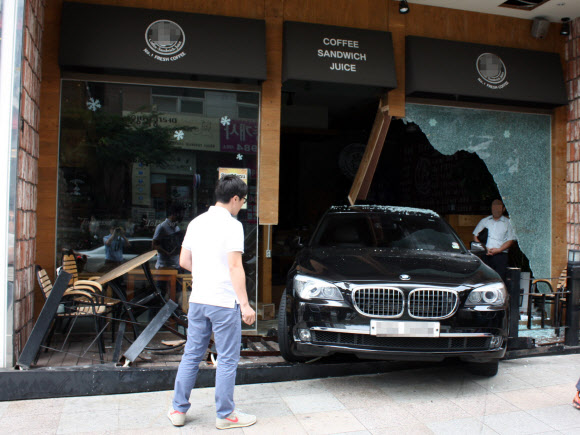 24일 오전 11시 40분께 부산 해운대구 좌동 모 커피숍 앞에서 후진하던 배모(58)씨의 BMW 승용차가 커피숍 유리벽을 부수고 돌진해 있다.  << 해운대경찰서 제공 >>