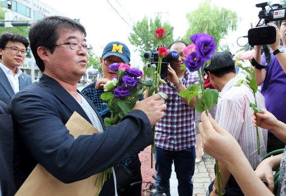 안도현(52·우석대 교수) 시인이 1일 공직선거법위반 혐의에 대해 첫 재판을 받기 위해 전주지법 출두하며 지지자들에게 격려의 꽃을 받고 있다. 연합뉴스