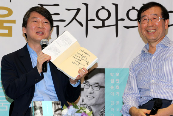 안철수(왼쪽) 무소속 의원이 7일 오후 서울 마포구 동교동 가톨릭청년회관에서 열린 박원순 서울시장의 출판 기념 토크 콘서트에 특별 게스트로 참석해 박 시장의 사인이 담긴 책을 언론에 공개했다. 연합뉴스