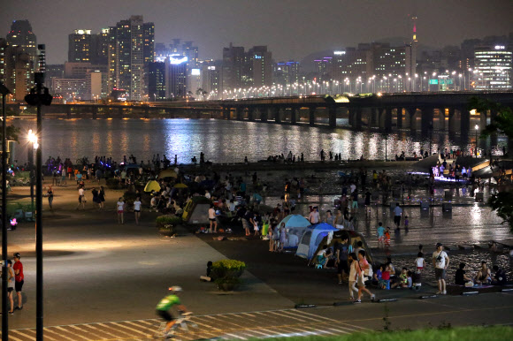 연일 열대야가 계속되는 가운데 서울 여의도 물빛광장 분수를 찾은 시민이 더위를 식히고 있다.  연합뉴스
