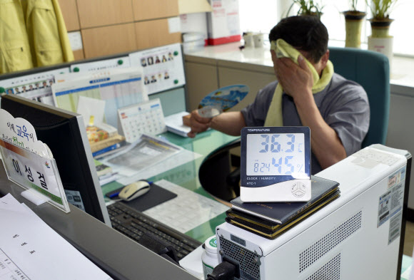 ‘헉 36.3도’ 더워 죽겠다 울산시교육청이 이틀째 냉방기 가동을 중단하면서 사무실 실내 온도가 36도를 넘어섰다. 13일 한 공무원이 이마에 수건을 두른 채 근무하고 있다. 연합뉴스