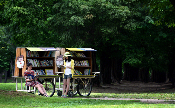 서울숲공원의 중앙에 비치한 ‘책수레’에서 시민들이 책을 골라 보고 있다. 관리자도 없고 독촉 전화도 하지 않지만 회수율이 85%를 웃도는 ‘양심 책수레’다.