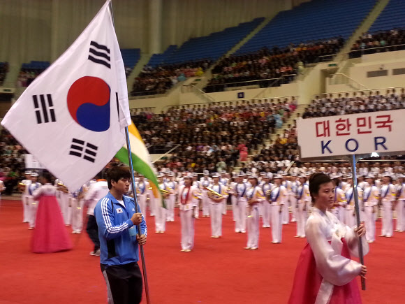 평양에 태극기 첫 등장…한국선수단, 개막식 참석 대한역도연맹은 지난 12일 평양 류경 정주영체육관에서 열린 대회 개막식에 한국 선수단의 기수 구원서(아산시청)가 태극기를 들고 입장했다고 13일 밝혔다. 한국 선수단을 인도하는 북한 여성 진행자의 피켓에는 ‘대한민국, KOR’이라는 정식 국호가 쓰여 있었다. 분단 이후 북한에서 열리는 스포츠 행사에 한국 선수단이 출전한 것은 몇 차례 있었으나 선수단이 태극기를 들고 ‘대한민국’ 국호를 사용한 것은 이번이 처음이다.  연합뉴스