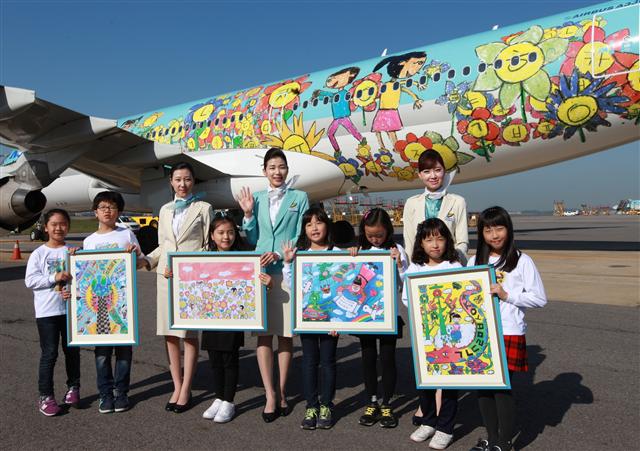 9일 김포공항 국내선 활주로 앞에서 대한항공 승무원들과 그림 그리기 대회에서 입상한 어린이들이 1등 작품으로 꾸며진 여객기를 배경으로 기념촬영을 하고 있다.  대한항공 제공