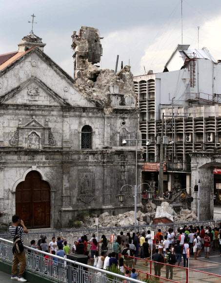 15일 필리핀 세부 인근 보홀섬에서 규모 7.2의 강진이 발생한 가운데 주민들이 지진의 여파로 일부가 붕괴된 바실리카 미노레 델 산토니뇨 성당을 바라보고 있다. 세부 AP 연합뉴스