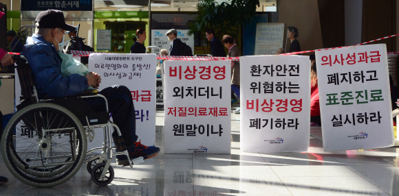 서울대병원 노조가 2007년 이후 6년 만에 총파업에 돌입한 23일 서울 종로구 연건동 서울대병원 본관에서 휠체어를 탄 환자가 파업 시위 문구를 바라보고 있다. 