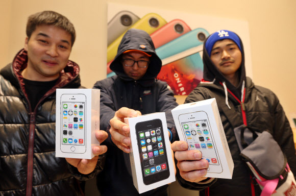 애플의 신제품 아이폰5S, 5C 출시일인 25일 오전 서울 중구 명동의 한 전자기기 매장에서 제품을 구매한 손님들이 전화기를 들어보이고 있다.  연합뉴스