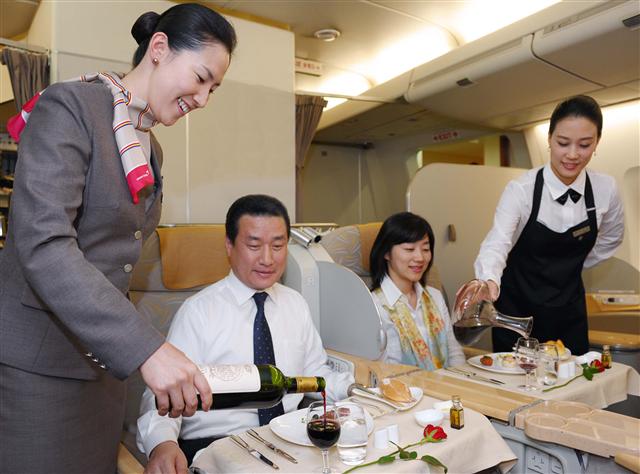여성 친화적 정책을 추구하는 아시아나항공의 소믈리에 승무원들이 기내에서 승객에게 와인을 제공하고 하고 있다.  아시아나항공 제공