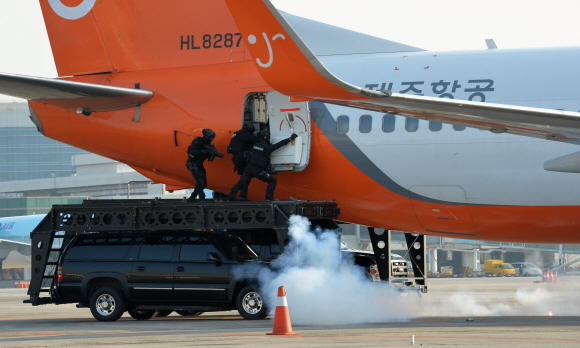 경찰특공대 대원들이 5일 서울 강서구 공항동의 김포국제공항 계류장에서 열린 대테러·항공기사고 수습 종합훈련에서 섬광탄을 던지며 테러범이 납치한 것으로 설정된 비행기 안으로 들어가고 있다. 손형준 기자 boltagoo@seoul.co.kr