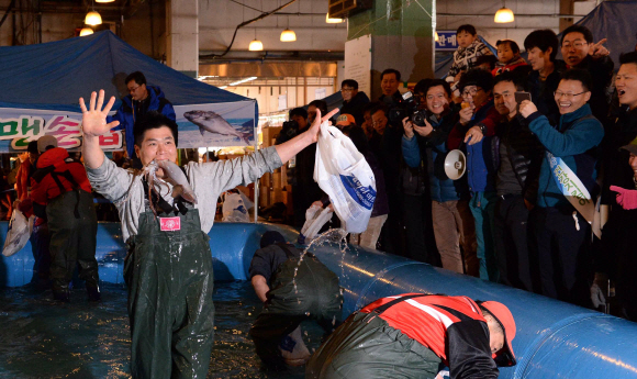 ‘2013 전국 수산물 한마당 대축제’에 참가한 한 시민이 17일 활어 맨손 잡기 행사에서 잡은 오징어를 입에 물고 기뻐하고 있다. 행사는 지난 16일부터 이틀 동안 서울 동작구 노량진수산시장에서 수협중앙회 주최로 열렸다. 이언탁 기자 utl@seoul.co.kr