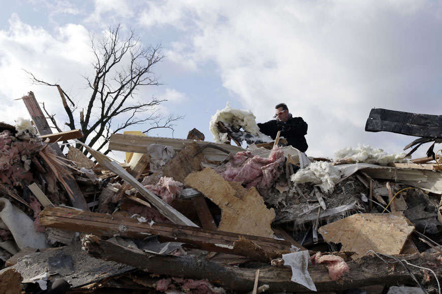 18일(현지시간) 강력한 토네이도가 휩쓸고 지나가면서 형체를 알아볼 수 없을 정도로 무너진 집에서 한 남성이 잔해들을 살펴보고 있다. AP/뉴시스