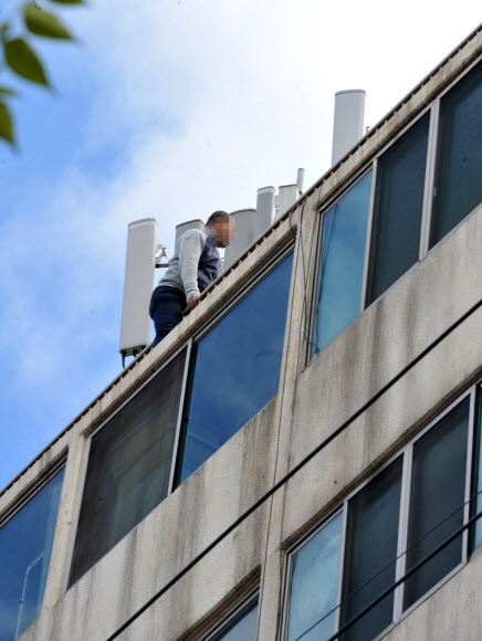 22일 낮 제주시 연동 모 아파트 7층 옥상에서 한 중국인 관광객이 자살 시도 소동을 벌이고 있다.  연합뉴스