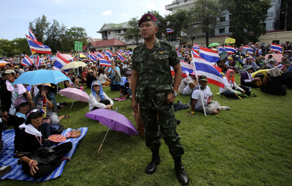 잉락 친나왓 태국 총리의 하야를 요구하는 반정부 시위대가 29일 방콕 육군본부를 점거해 시위를 벌이고 있는 가운데 한 군인이 우려 섞인 눈길로 한 곳을 바라보고 있다. 방콕 AP 연합뉴스