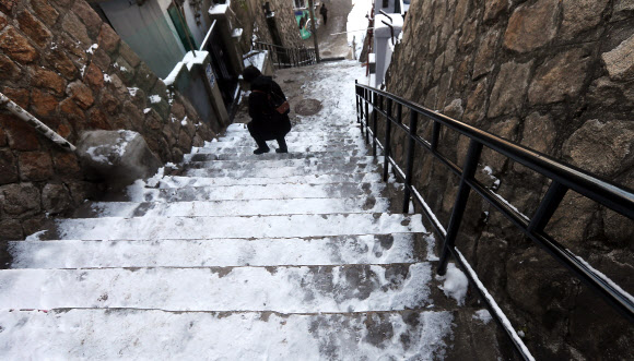 13일 오전 출근길 시민이 꽁꽁 얼어붙은 서울 종로구 이화마을 계단을 내려가고 있다. 연합뉴스