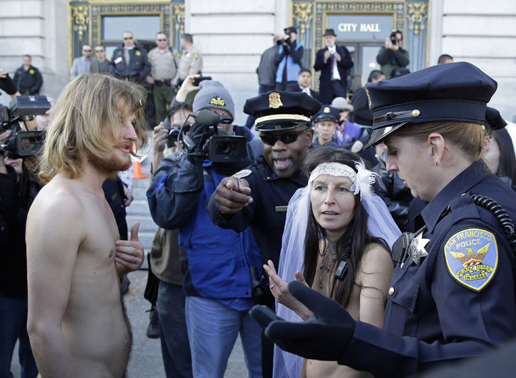 19일(현지시간) 미국 샌프란시스코 시청사 앞에서 알몸 결혼식을 한 집시 타우브(오른쪽·Gypsy Taub)와 제이미 스미스(왼쪽·Jaymz Smith)가 경찰들에 의해 밖으로 끌려 나가고 있다. AP=뉴시스