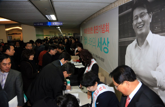 지난달 21일 국회 도서관 대회의실에서 열린 윤상현 새누리당 원내수석부대표의 ‘정치 너머의 세상’ 출판기념회 참석 인사들이 줄을 서 책을 구입하고 있다.  연합뉴스