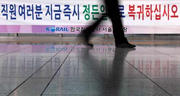 철도파업 21일째인 29일 오후 서울역에서 한 시민이 복귀를 호소하는 플래카드 앞을 지나고 있다. 연합뉴스