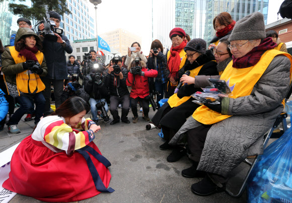 갑오년 새해 첫날인 1일 오후 서울 종로구 주한 일본대사관 앞에서 열린 ‘일본군 위안부 문제 해결을 위한 정기 수요시위’에서 한 참가자가 할머니들에게 세배를 드리고 있다. 연합뉴스