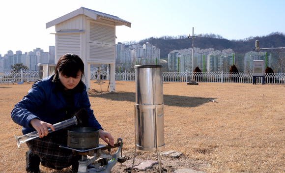 서울 종로구 송월동 기상관측소의 관측장에서 적설량을 관측하고 있다. 뒤편의 백엽상 안에는 온도센서가 들어 있다.