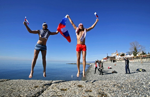 13일(현지시간) 동계올림픽이 열리고 있는 소치의 아들레르 해변에서 러시아인 2명이 국기를 들고 점프하고 있다. 로이터/뉴스1
