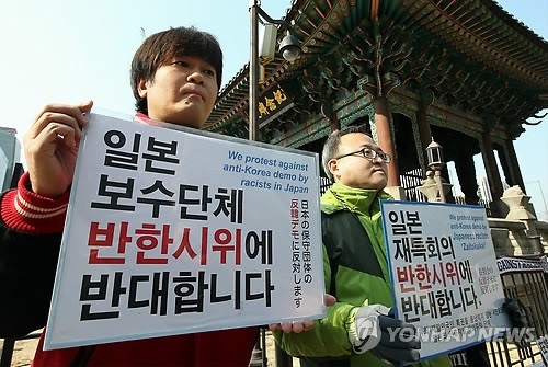 사쿠라이 노부히데 남서울대학교 교수(왼쪽)와 친구가 함께 15일 서울 광화문 교보빌딩 앞에서 반한시위 반대 메시지가 적힌 손팻말을 들고 있다.  연합뉴스