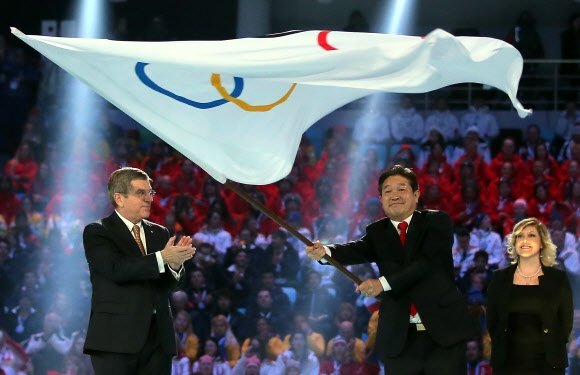 이석래(오른쪽) 평창군수가 토마스 바흐(왼쪽) 국제올림픽위원회(IOC) 위원장이 건넨 올림픽기를 받아 든 뒤 힘차게 펄럭이고 있다.  연합뉴스