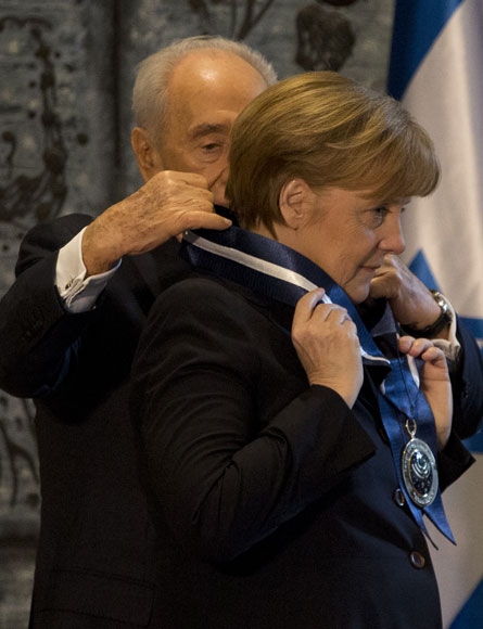 시몬 페레스 이스라엘 대통령(왼쪽)이 25일(현지시간) 예루살렘에 있는 대통령 관저에서 앙겔라 메르켈 독일 총리에게 ‘명예시민 메달’을 걸어주고 있다.  이스라엘=신화/뉴시스